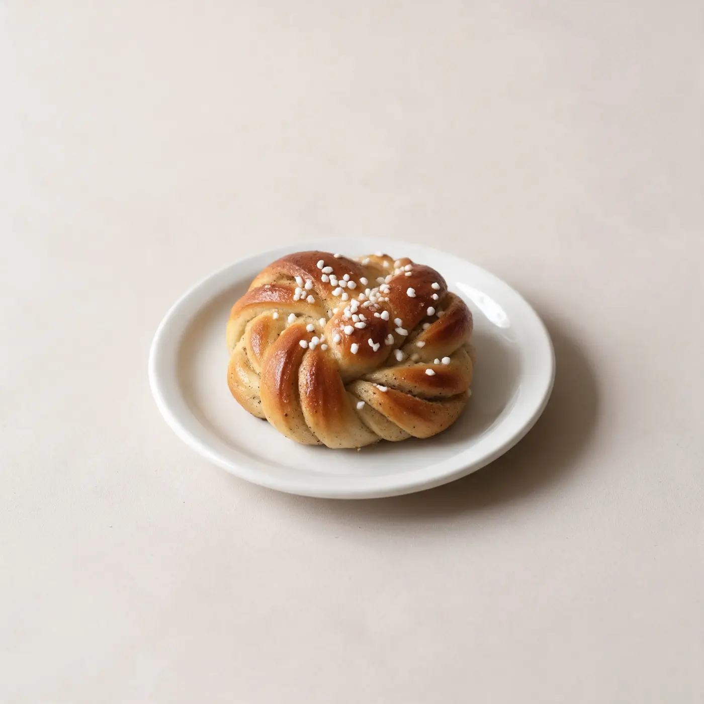 A cardamom bun on a small white plate.